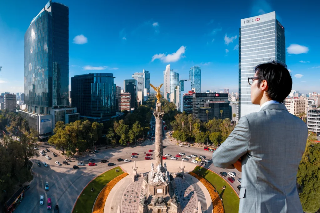 Hombre de negocios observando el Ángel de la Independencia y los edificios corporativos de la Ciudad de México representando el análisis del entorno empresarial