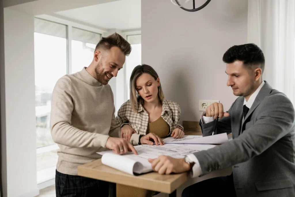Agente inmobiliario mostrando planos de casas a clientes para respaldar la decisión de compra con datos del mercado