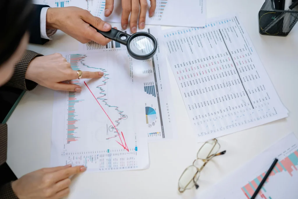 Investigadores analizando gráficas de costos sobre una mesa para evaluar el impacto económico de los errores en la toma de decisiones