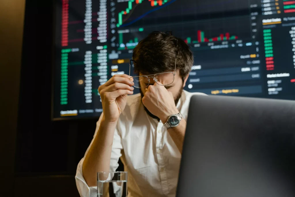 Analista de mercado frente a una computadora, preocupado por los datos financieros