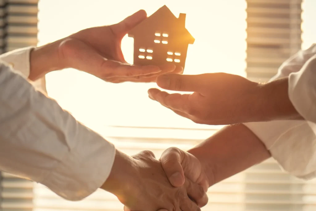 Dos personas estrechando la mano frente a una casa, simbolizando una decisión inmobiliaria respaldada por un investigador de mercado
