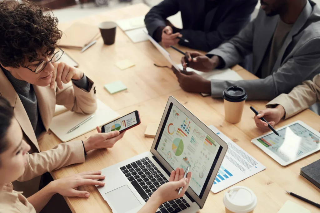 Grupo de personas analizando gráficas en computadora, teléfono y tablet, mostrando cómo la investigación de mercados reemplaza la intuición con datos
